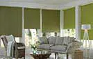 Warm green roller blinds installed in a bright room with natural light filtering through.