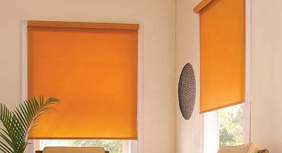 Light orange blackout roller blinds partially lowered on a window in a minimalist room.