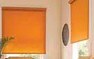 Light-filtering cream roller blinds allowing soft sunlight to brighten a modern interior.